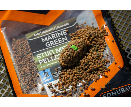 marine 3 - freddiethepillowandfriends.co.uk Outdoor close-up of Marine Green fishing bait pellets spilled on an orange package, with a single bait nugget resting on top.